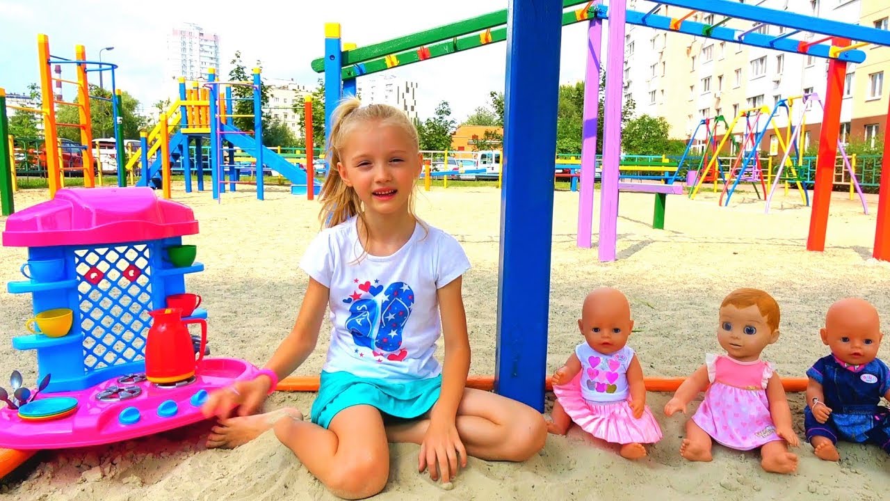 Funny Polina playing with Colored cups and baby dolls on the playground
